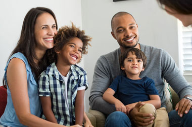 Joyful diverse family relaxing on couch, symbolizing accessible FHA loans in New York and Pennsylvania